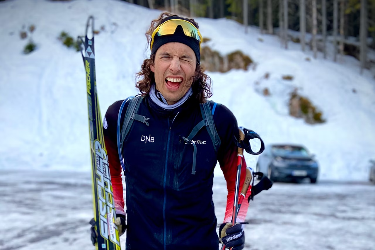 Mann med ski smiler bredt