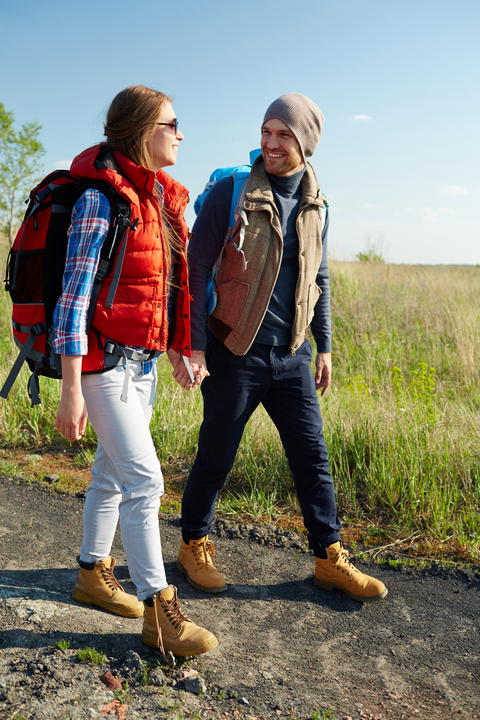 Couple of young travelers with backpacks smiling and talking whi